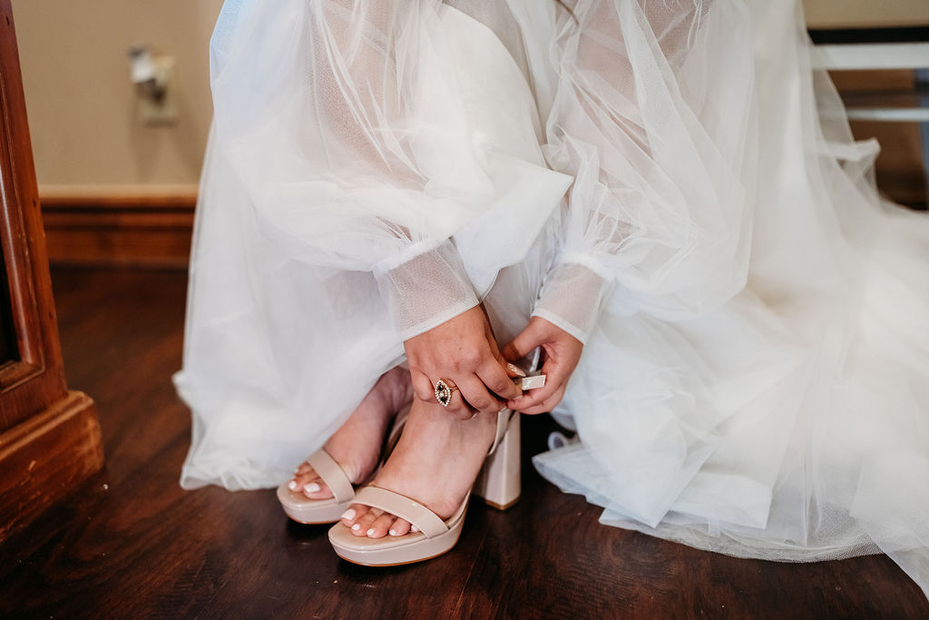 bride placing on nude heals. champagne heals