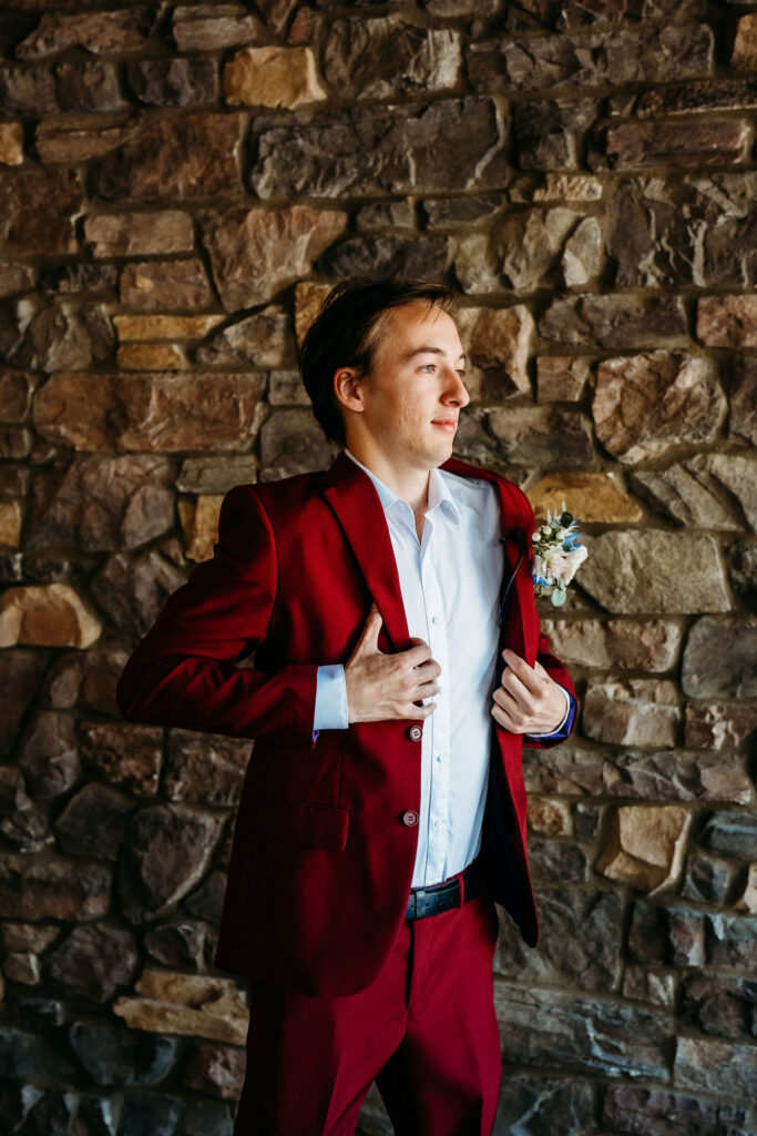 groom in maroon suit, groom putting jacket on