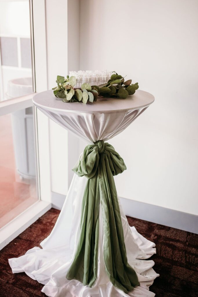 wedding details, table with sage green bow and sage florals with bubbles