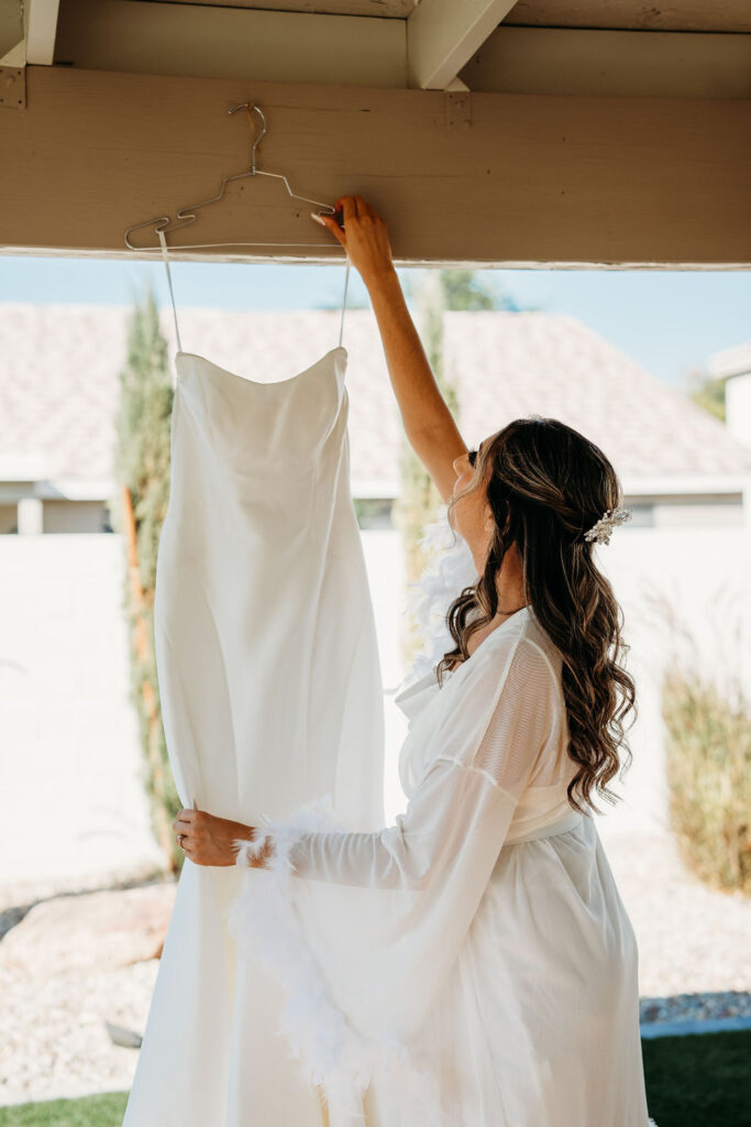 simple white wedding dress, spaghetti strap wedding dress, bride looking at wedding dress