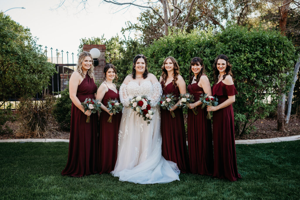 Bride and bridesmaid in a long maroon dress. At Stonebridge Manor. Wedding party posing.