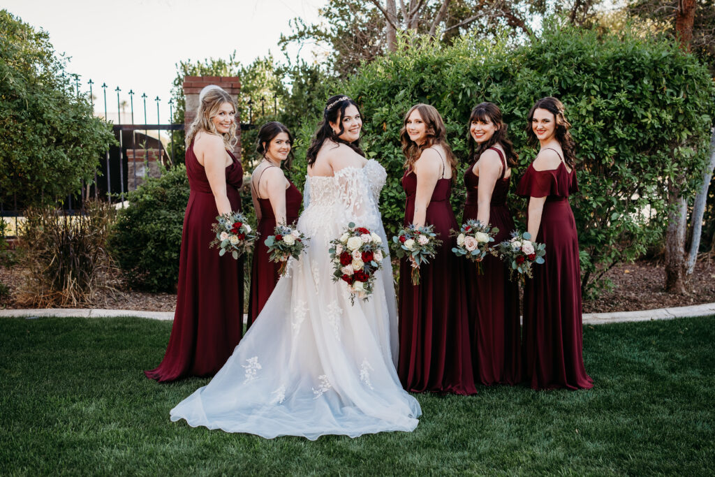 Bride and bridesmaid in a long maroon dress. At Stonebridge Manor. Wedding party posing.