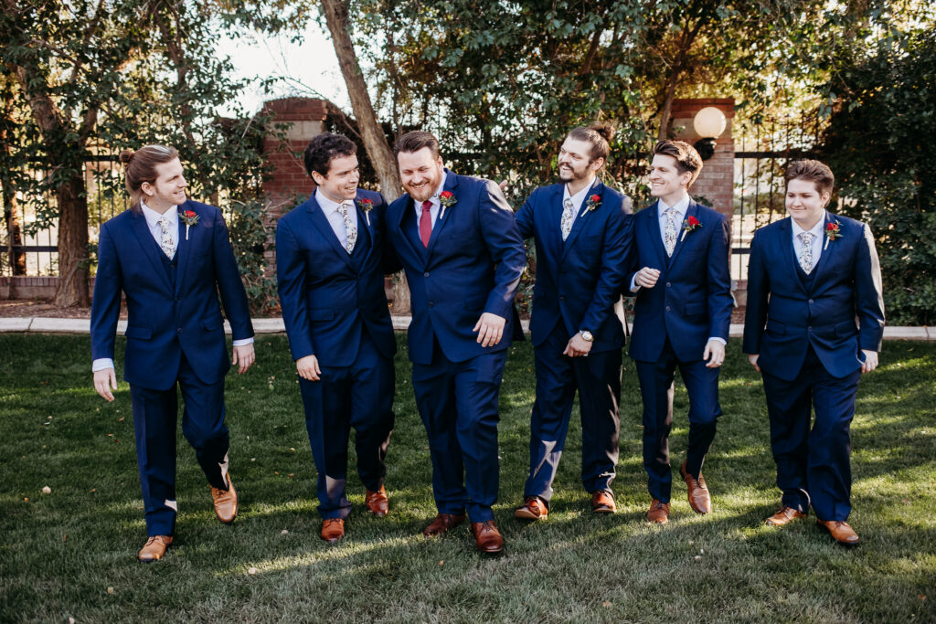 Groom and groomsmen in navy blue suit with maroon tie at Stonebridge Manor. Wedding party posing.