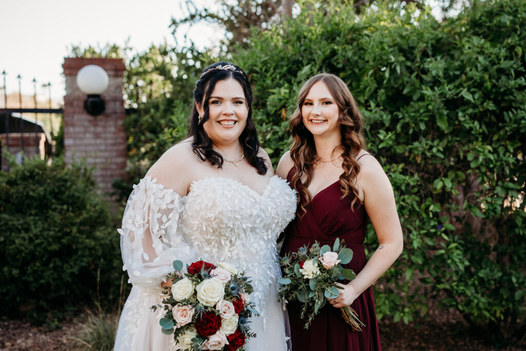 Bride and bridesmaid in a long maroon dress. At Stonebridge Manor. 