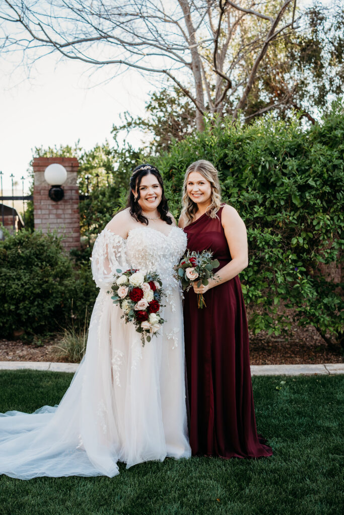 Bride and bridesmaid in a long maroon dress. At Stonebridge Manor. 