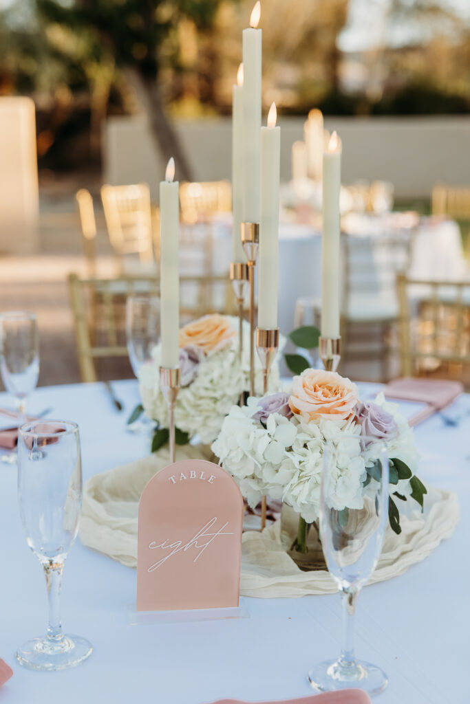 wedding table scape of roses, wedding colors of peach, lilac, tall candles