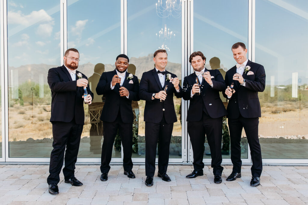 groom and groomsmen, black tux with pink tie, groomsmen posing ideas, arizona wedding photographer, groomsmen toasting with beer