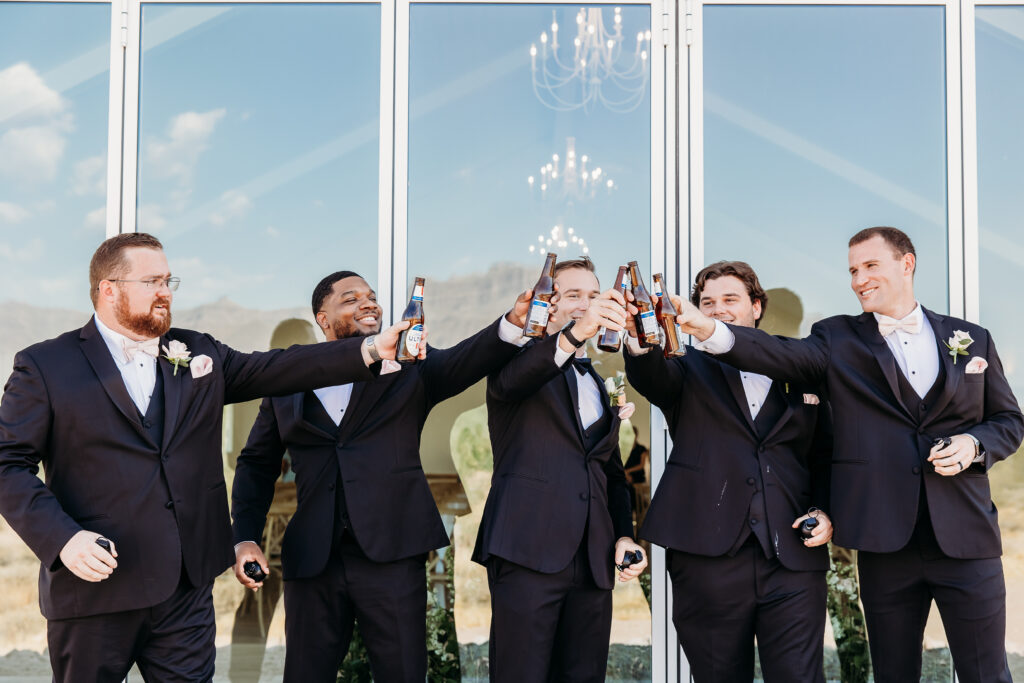 groom and groomsmen, black tux with pink tie, groomsmen posing ideas, arizona wedding photographer, groomsmen toasting with beer