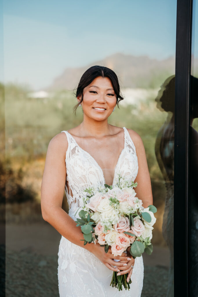 bride holding pink and white rose bouquet, bridal portraits, bride posing ideas, deep v neck wedding dress with floral details