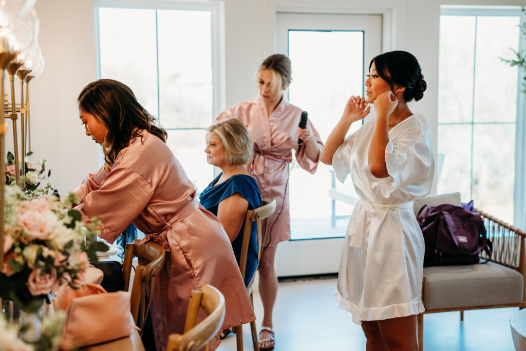 bride getting ready for wedding in white silk robe