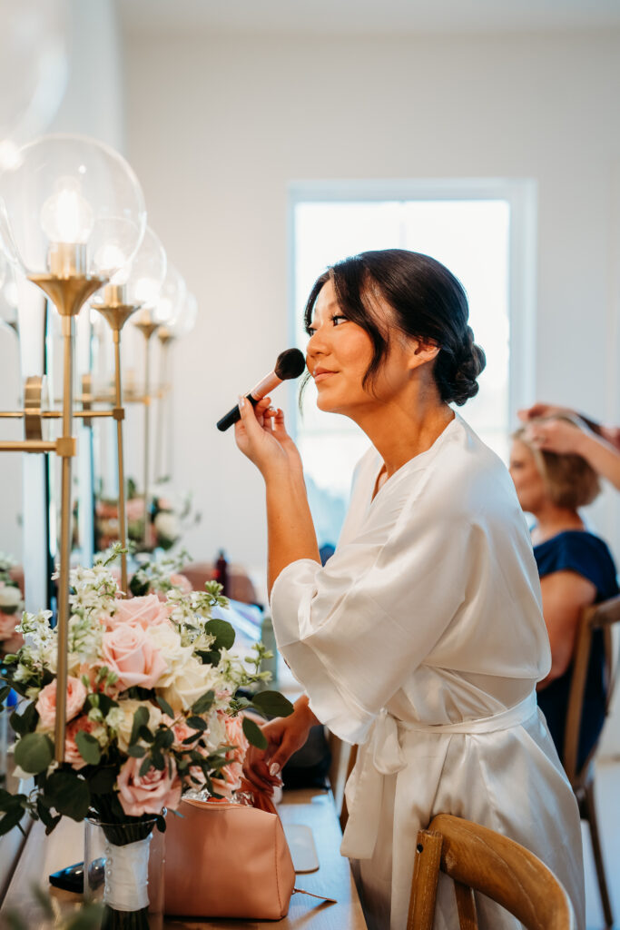 bride getting ready for wedding in white silk robe