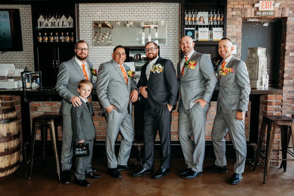 Groomsmen in grey tux and orange tie, bright boutonniere, wedding party posing ideas, arizona wedding photographer