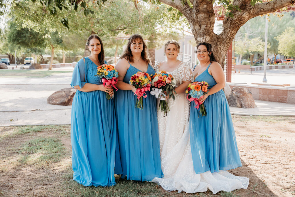 Bride and bridesmaid posing ideas, bridesmaid long bright blue dress, bright floral bouquets, gerber daisy and rose bouquets