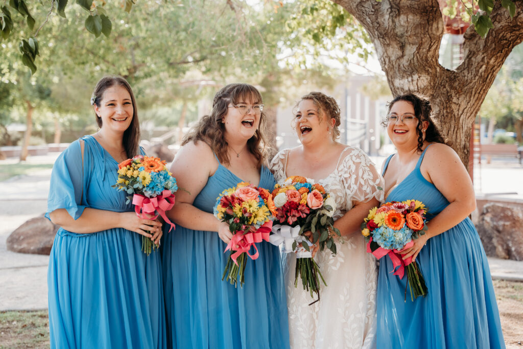 Bride and bridesmaid posing ideas, bridesmaid long bright blue dress, bright floral bouquets, gerber daisy and rose bouquets, arizona wedding photographer