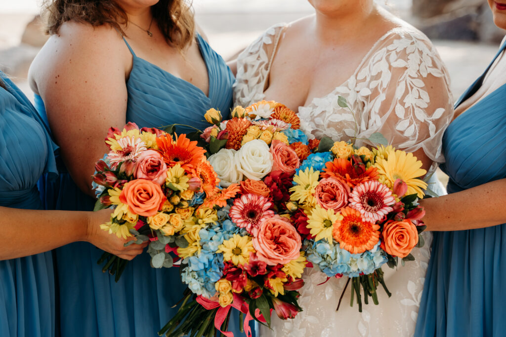 Bride and bridesmaid posing ideas, bridesmaid long bright blue dress, bright floral bouquets, gerber daisy and rose bouquets, arizona wedding photographer