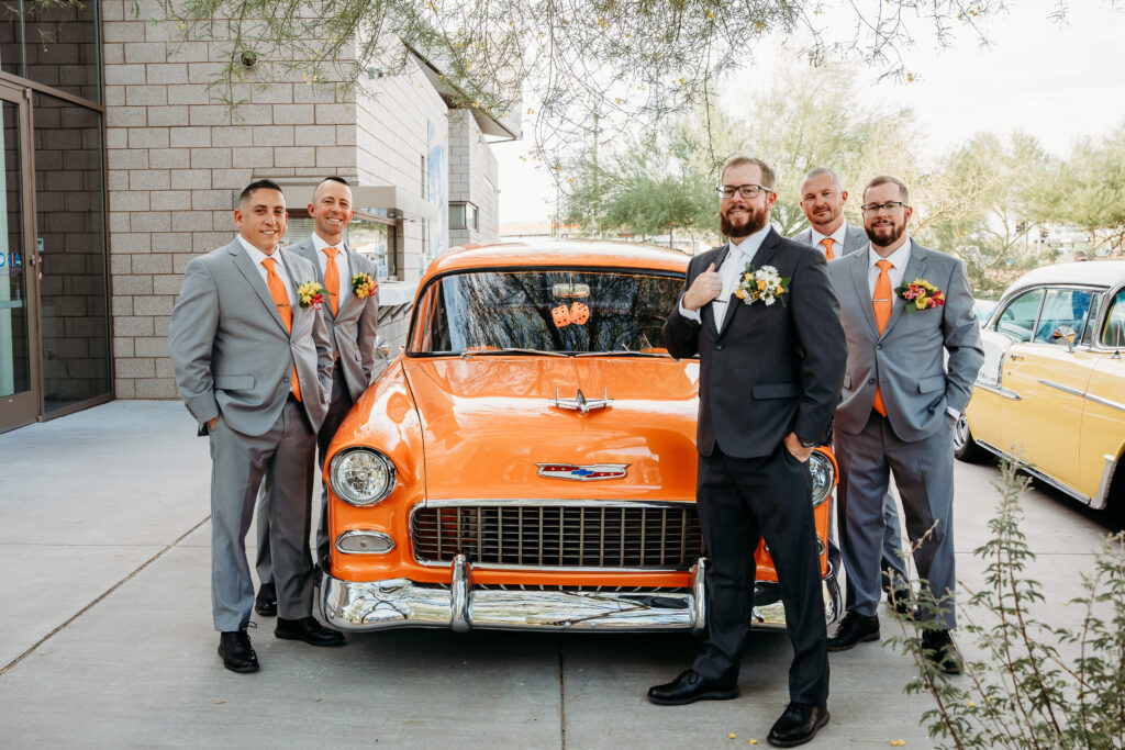 Groomsmen in grey tux and orange tie, bright boutonniere, classic car, wedding party posing ideas, arizona wedding photographer