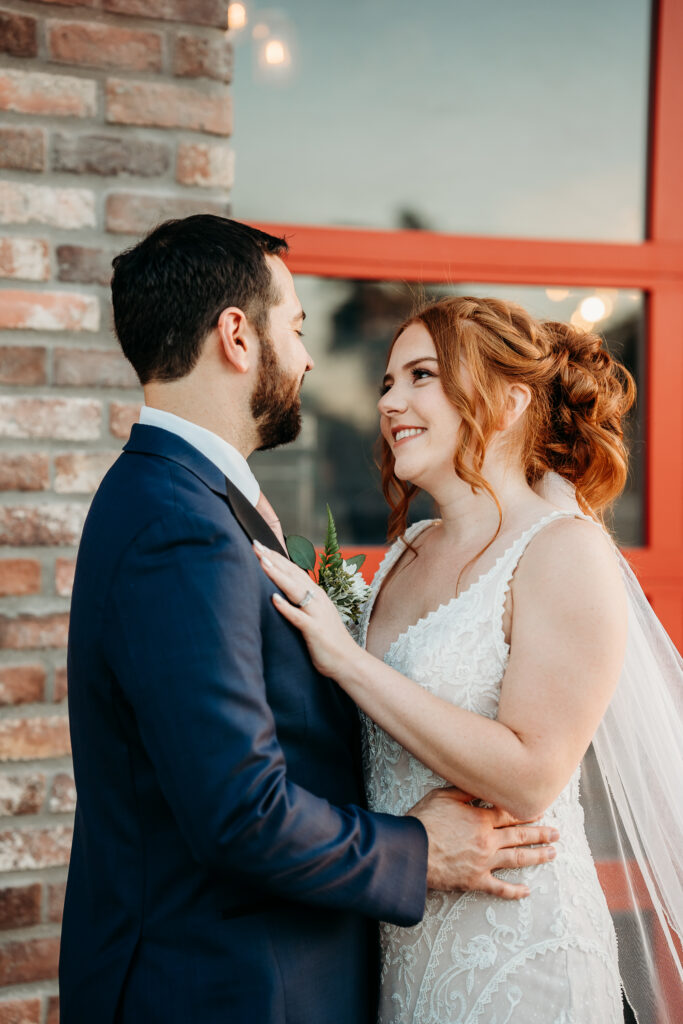 bride and groom posing ideas, bride in deep plunge neck line, updo with poppy and rose bouquet, fire house event center