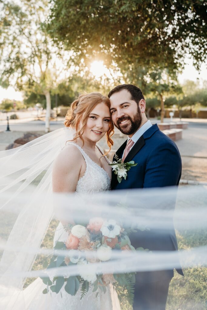 bride and groom posing ideas, arizona wedding photographer, groom in navy blue tux, bride in plunge neck line, wedding photo with train