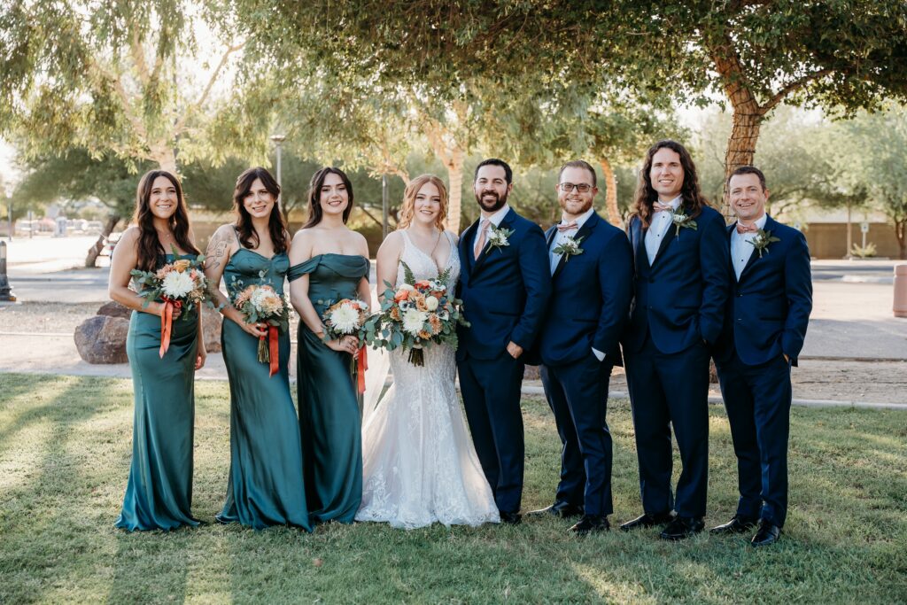 wedding party posing ideas, groomsmen in navy blue tux, bridesmaids in long deep green dresses