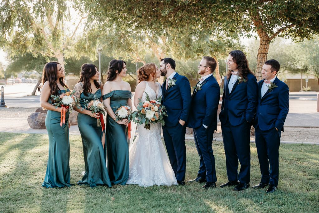 wedding party posing ideas, groomsmen in navy blue tux, bridesmaids in long deep green dresses