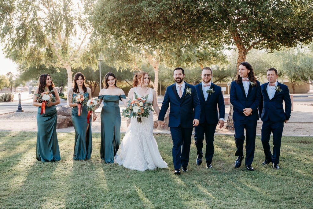 wedding party posing ideas, groomsmen in navy blue tux, bridesmaids in long deep green dresses