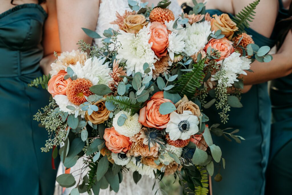 wedding bouquet of orange roses , poppies and white dahlias