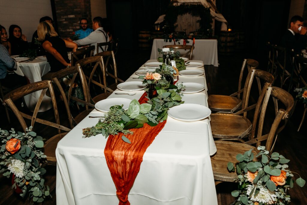 fire house event center, orange table runner ith greenery tablescape