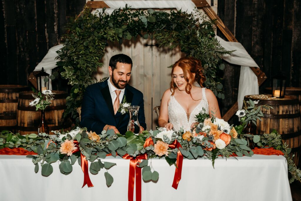 bride and groom sweetheart table at the fire house event center, sage green and orange wedding colors