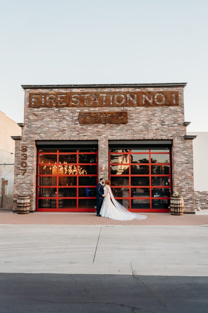 bride and groom posing ideas, bride in deep plunge neck line, updo with poppy and rose bouquet, fire house event center