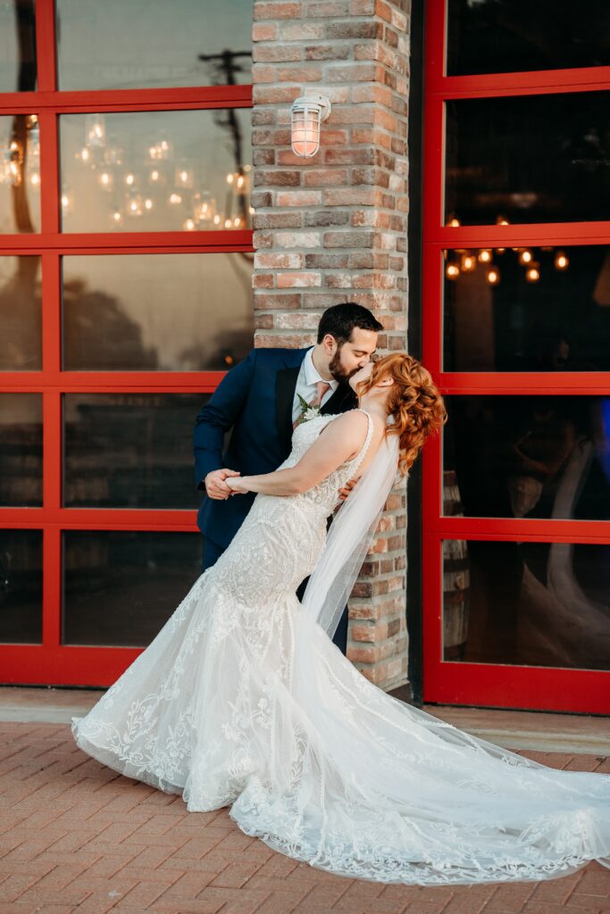 bride and groom posing ideas, bride in deep plunge neck line, updo with poppy and rose bouquet, fire house event center