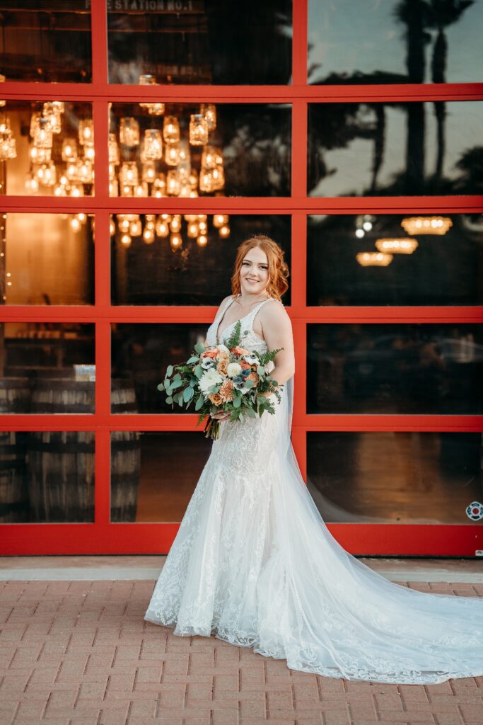 bride posing ideas, bride in deep plunge neck line, updo with poppy and rose bouquet, fire house event center
