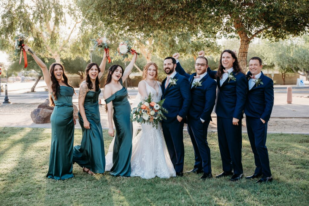 wedding party posing ideas, groomsmen in navy blue tux, bridesmaids in long deep green dresses