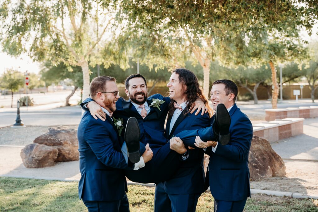 groom and groomsmen posing ideas, picking up groom, groom in navy blue tux