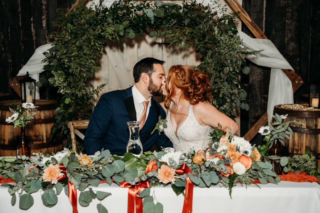 bride and groom sweetheart table at the fire house event center, sage green and orange wedding colors