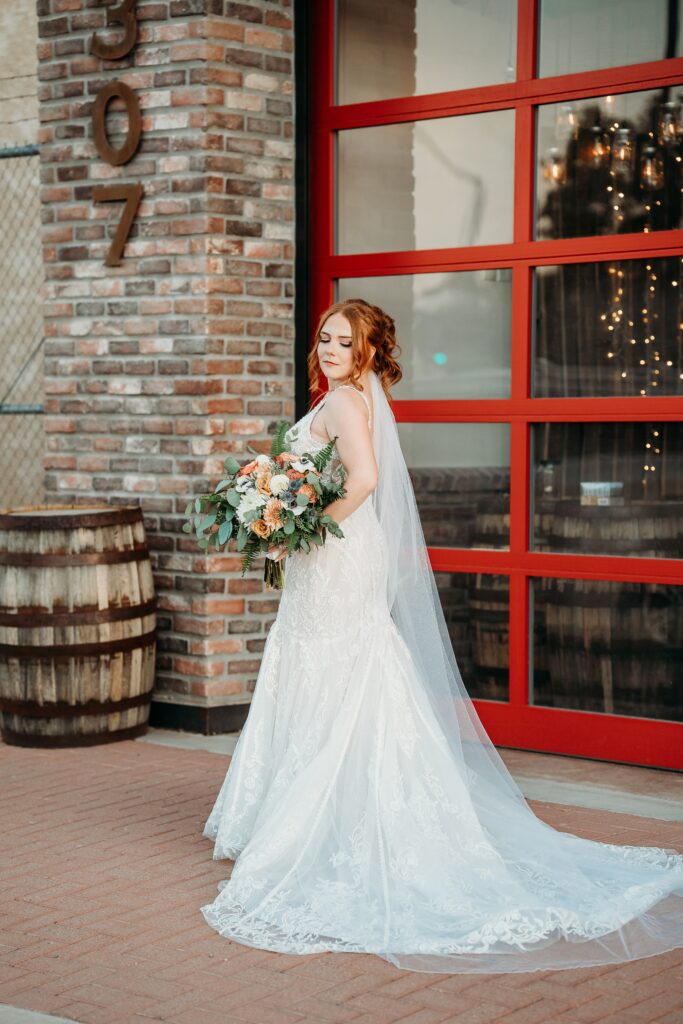 bride posing ideas, bride in deep plunge neck line, updo with poppy and rose bouquet, fire house event center