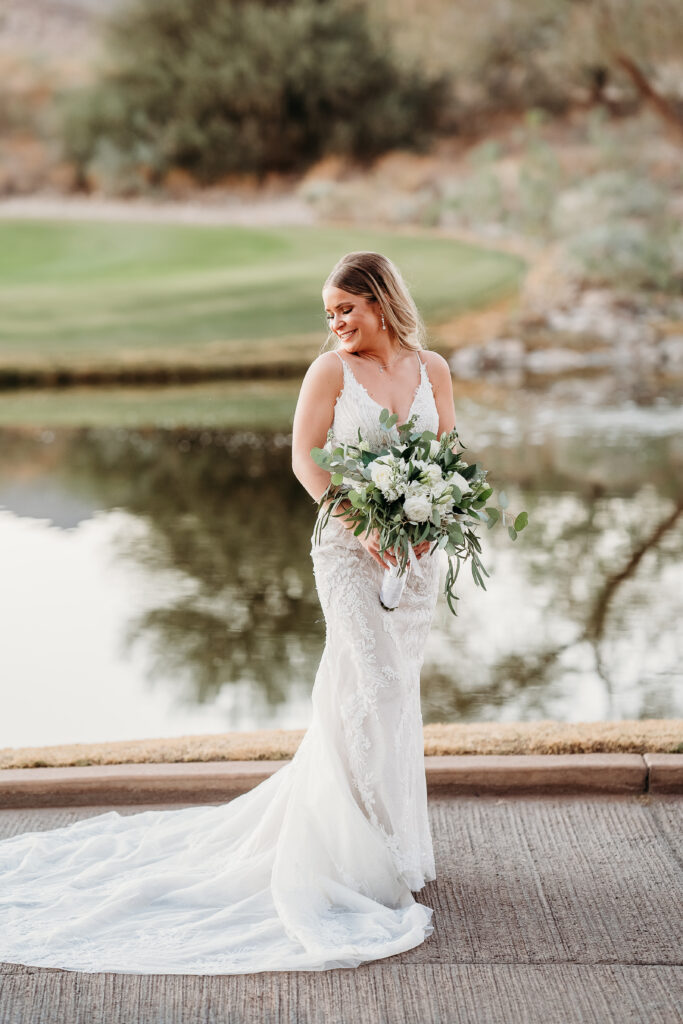 Bride Posing Ideas, bride in front of lake looking over shoulder, bride in long train,  bride in intricate wedding dress, arizona wedding photographer, bride at verrado golf club