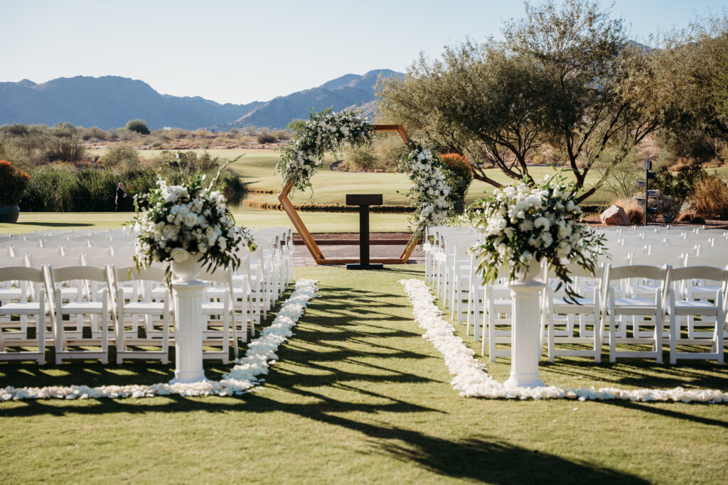 Groom kissing the bride at the end of the aisle at verrado golf club wedding ceremony, arizona wedding photographer, hexagon wood arch with white florals